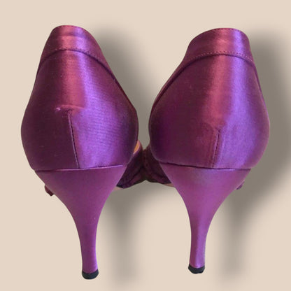 Pair of purple high-heeled shoes on a beige background