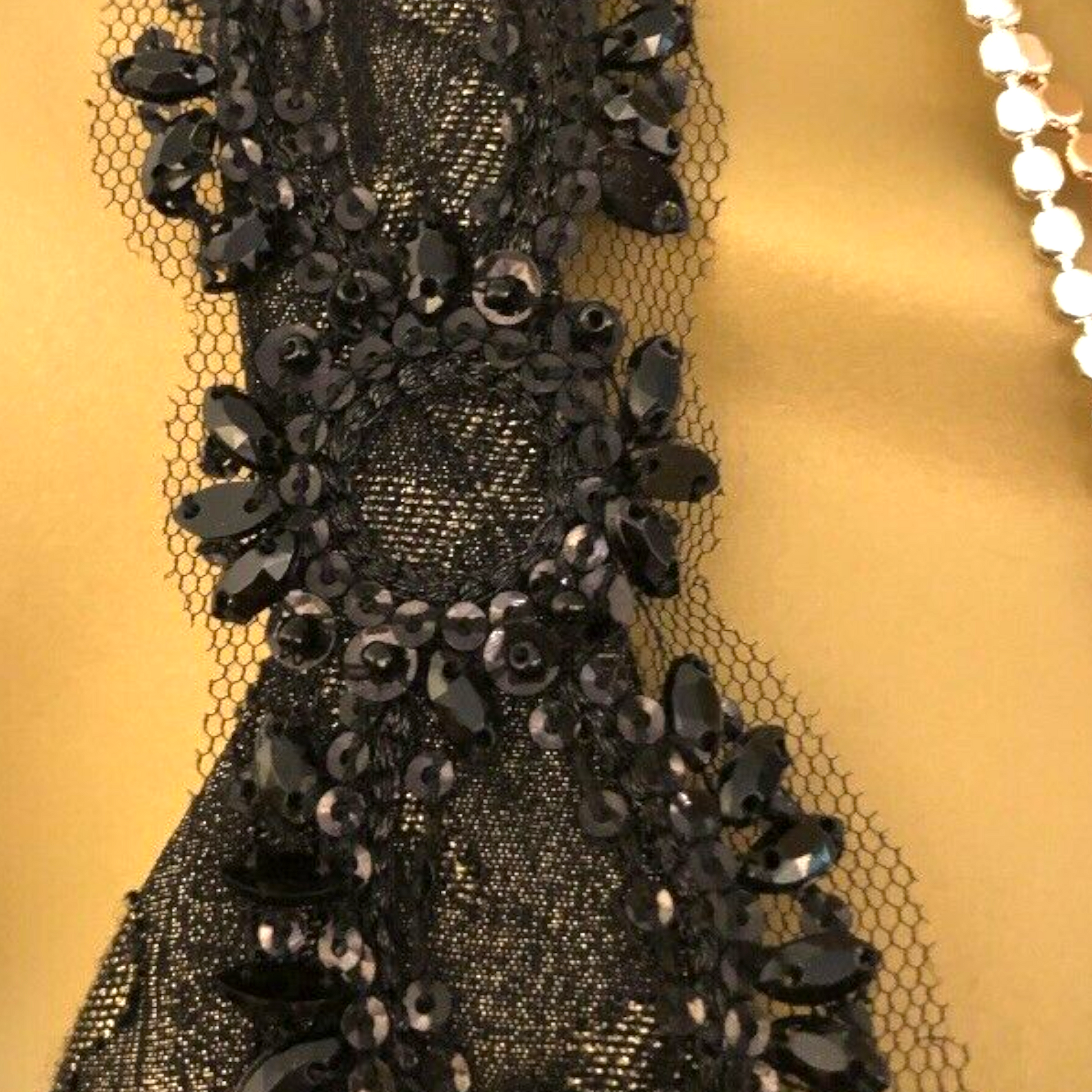 Close-up of a black beaded fabric on a gold background