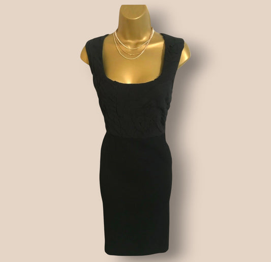 Black dress on a gold mannequin against a beige background
