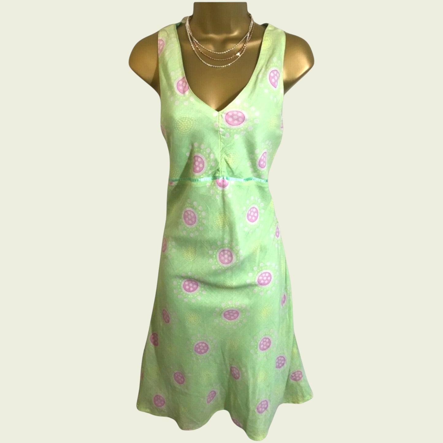 Green dress with pink floral pattern on a mannequin against a white background