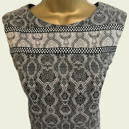 Mannequin wearing a sleeveless dress with snake print and checkered trim on a beige background