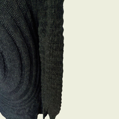Close-up of a dark gray knitted sweater sleeve on a beige background