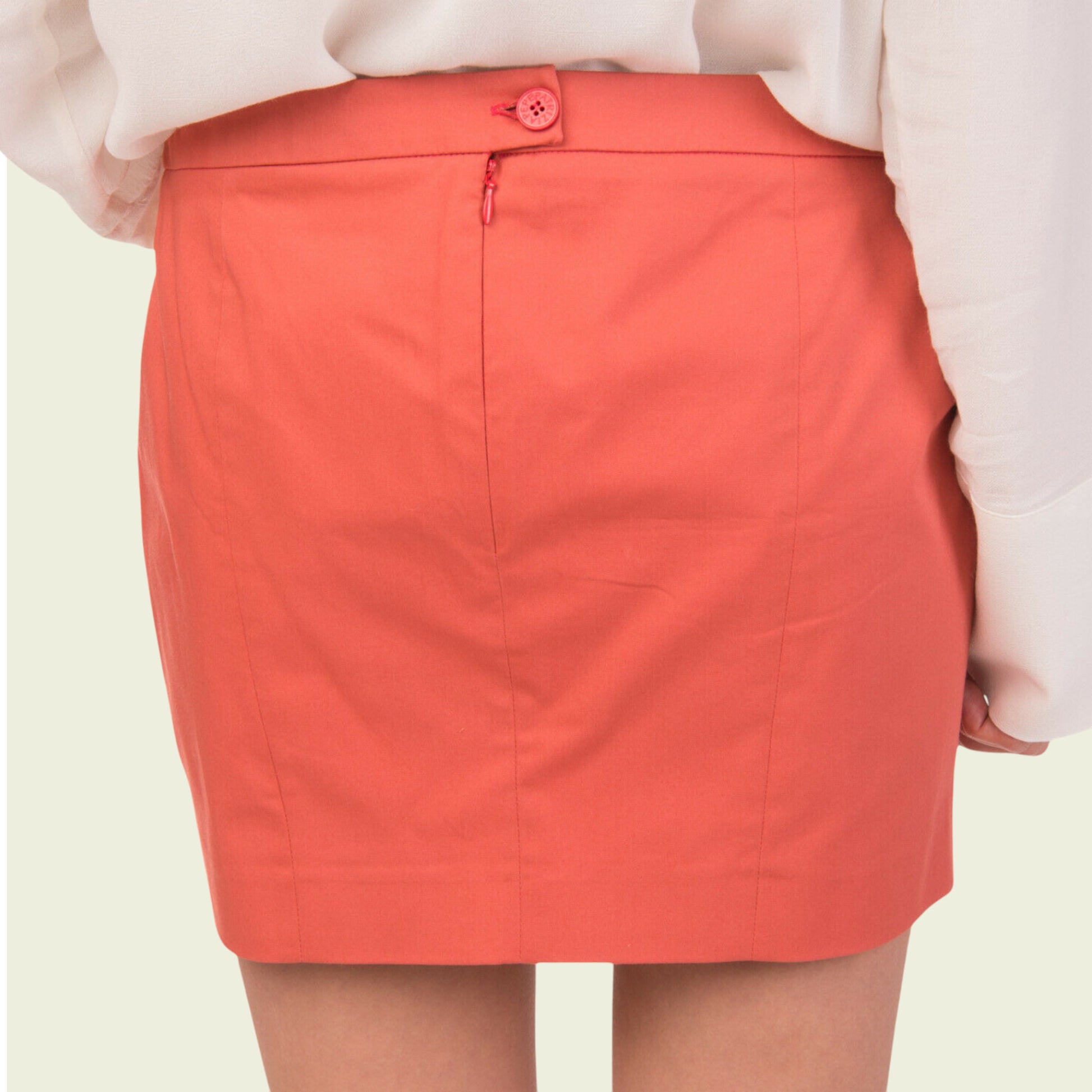Person wearing a coral skirt on a plain background