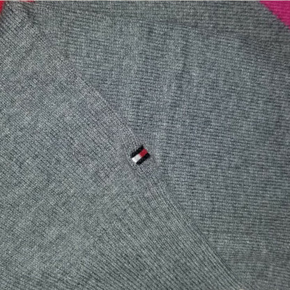 Close-up of a gray sweater with a small logo on the chest.