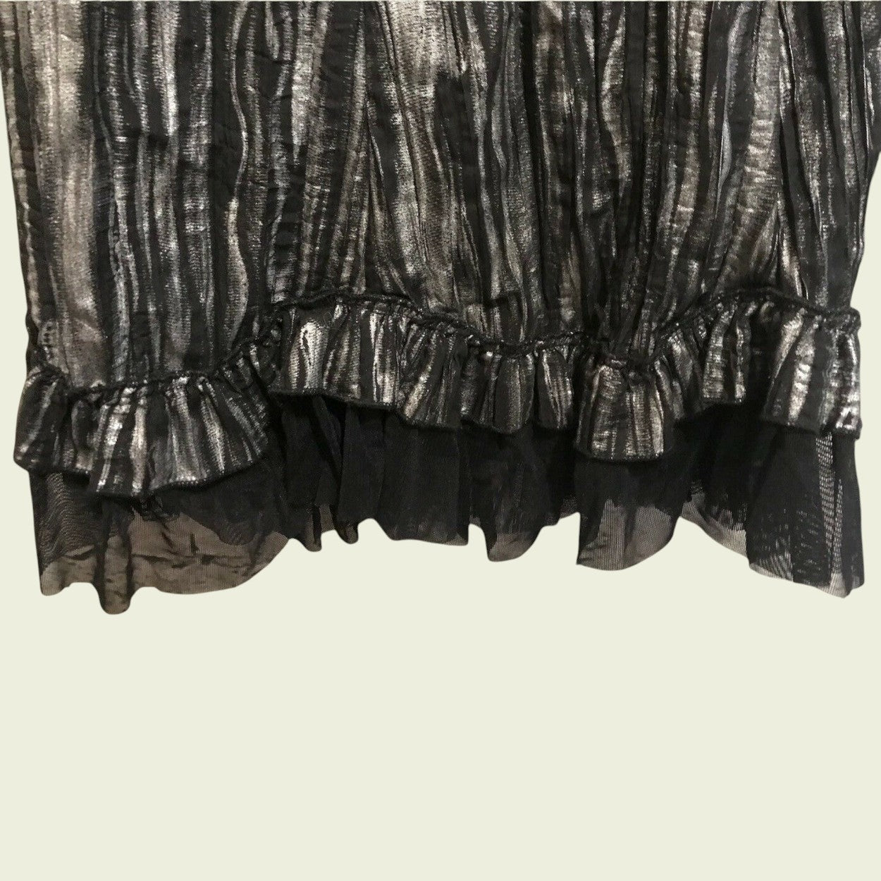 Close-up of a black and silver patterned skirt with ruffled layers on a beige background