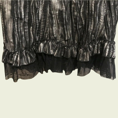 Close-up of a black and silver patterned skirt with ruffled layers on a beige background