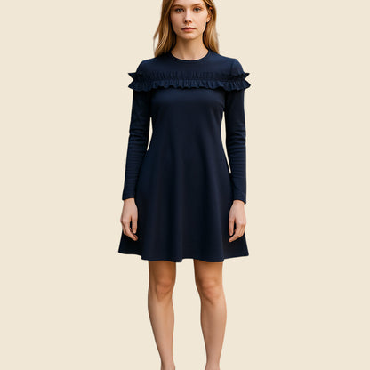 Woman wearing a navy dress with ruffled details on a beige background