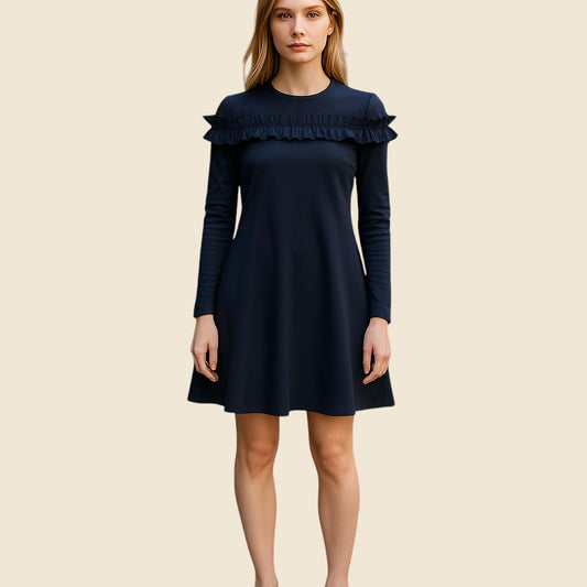 Woman wearing a navy dress with ruffled details on a beige background