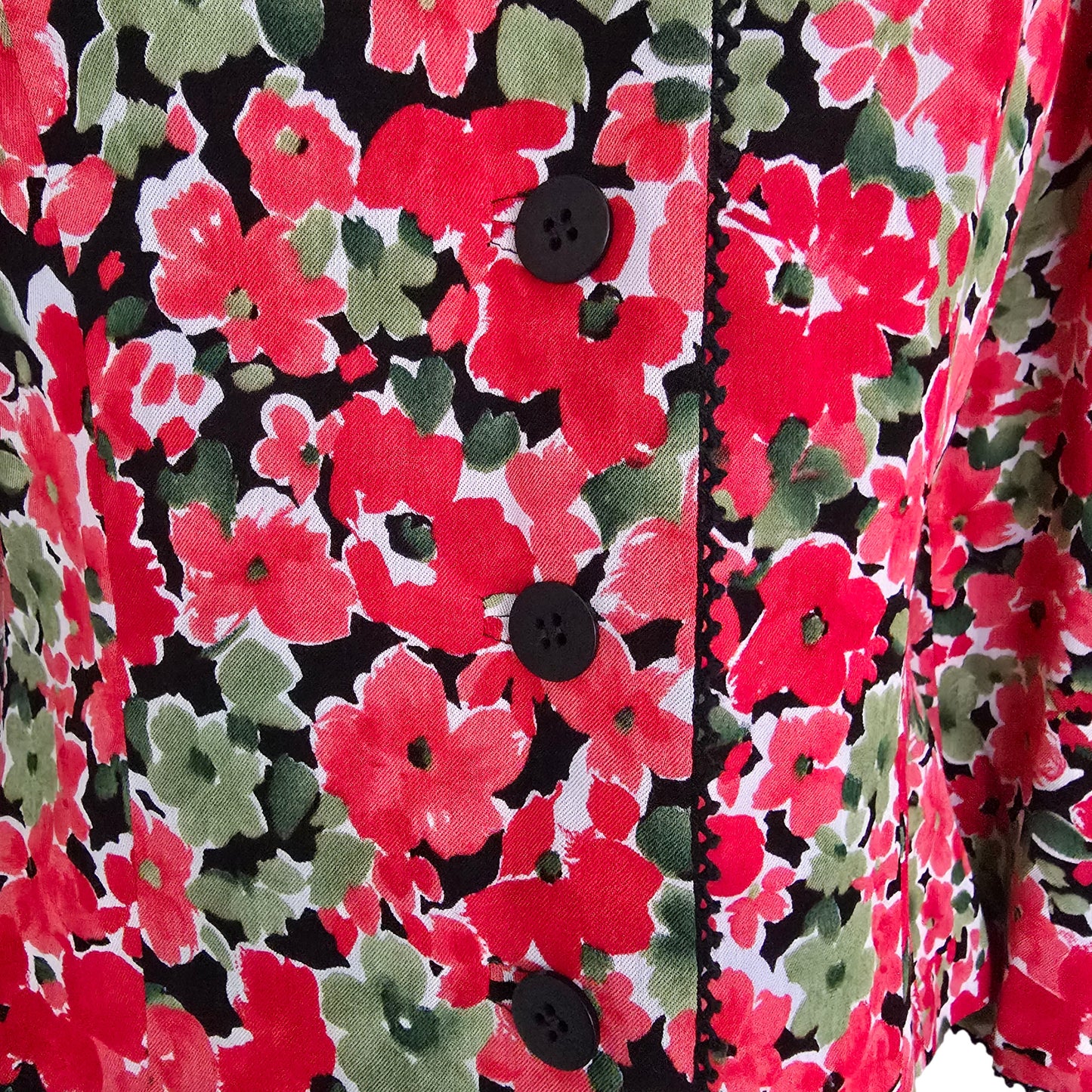 Close-up of a floral fabric with red, green, and black colors.