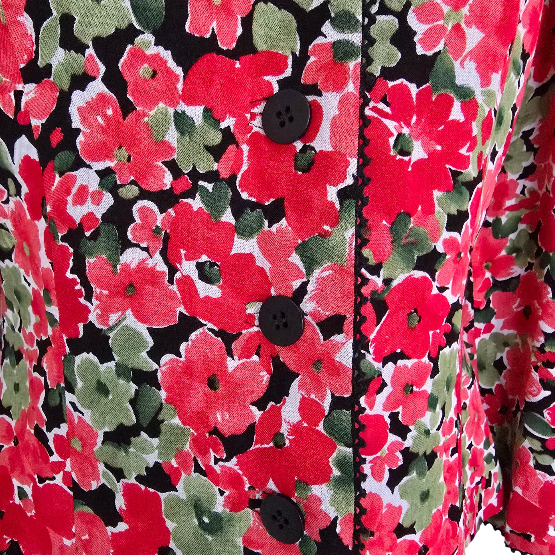 Close-up of a floral fabric with red, green, and black colors.