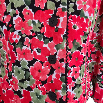 Close-up of a floral fabric with red, green, and black colors.