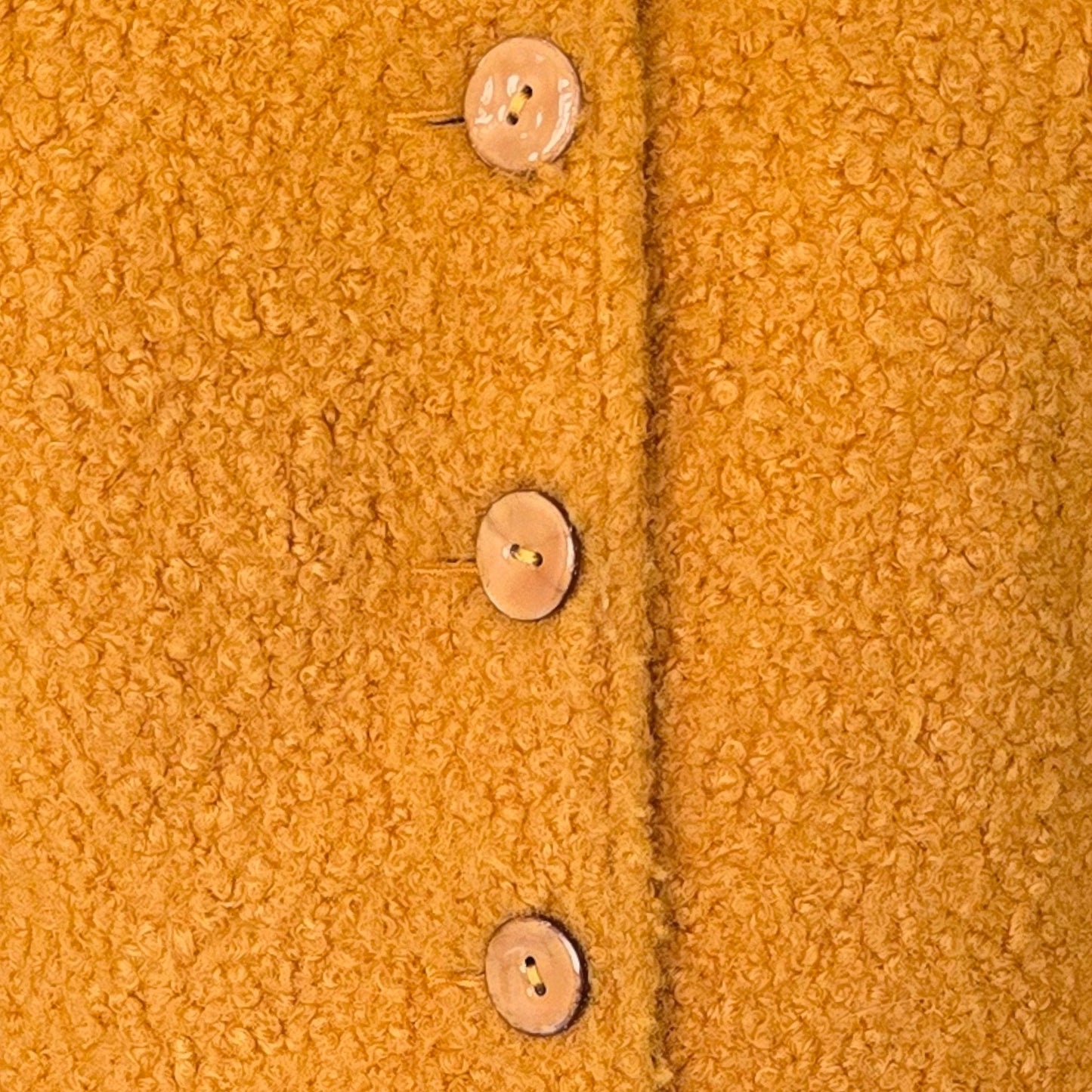 Close-up of a textured mustard yellow fabric with buttons.