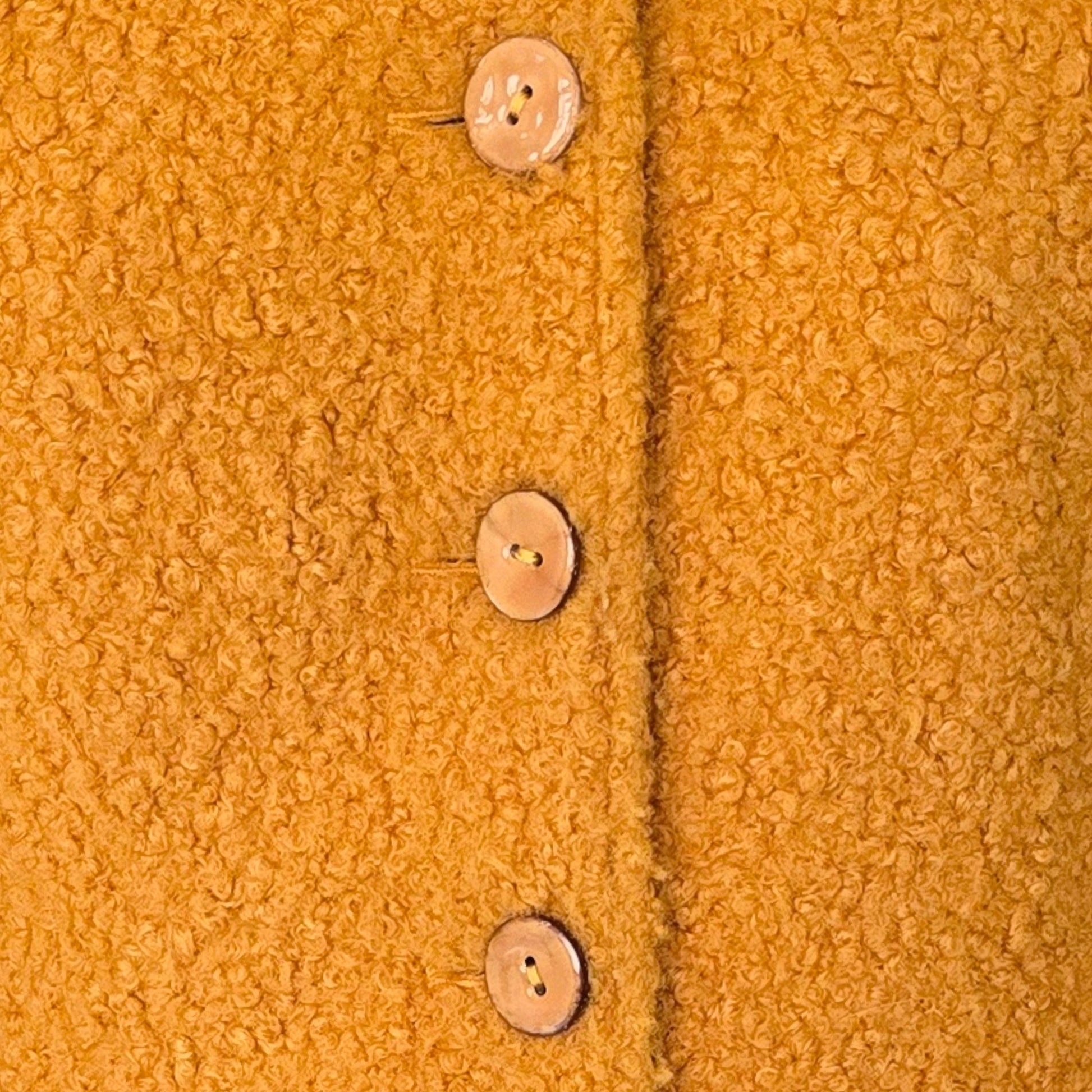 Close-up of a textured mustard yellow fabric with buttons.