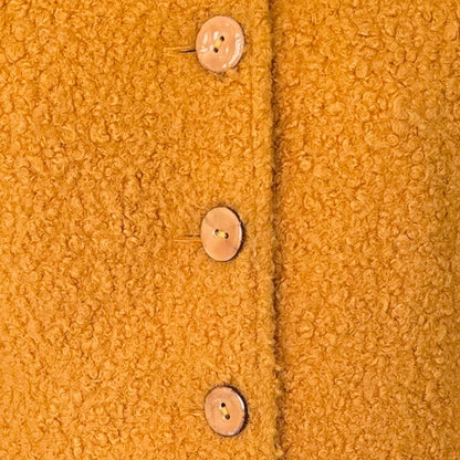 Close-up of a textured mustard yellow fabric with buttons.