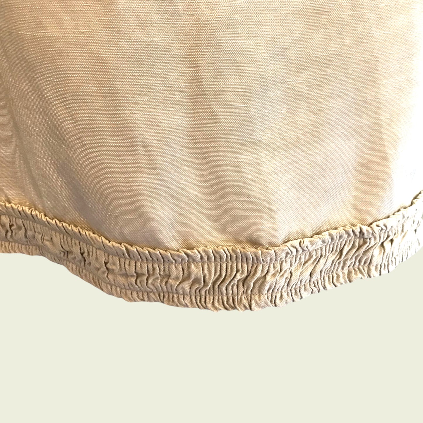 Ruched hemline of tan skirt on beige background