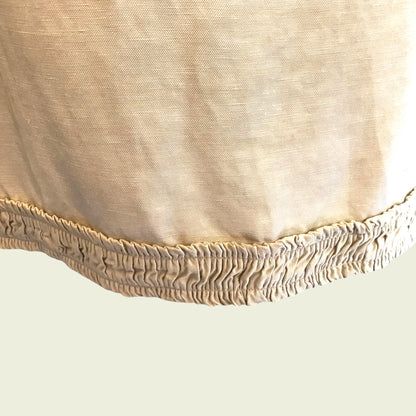 Ruched hemline of tan skirt on beige background