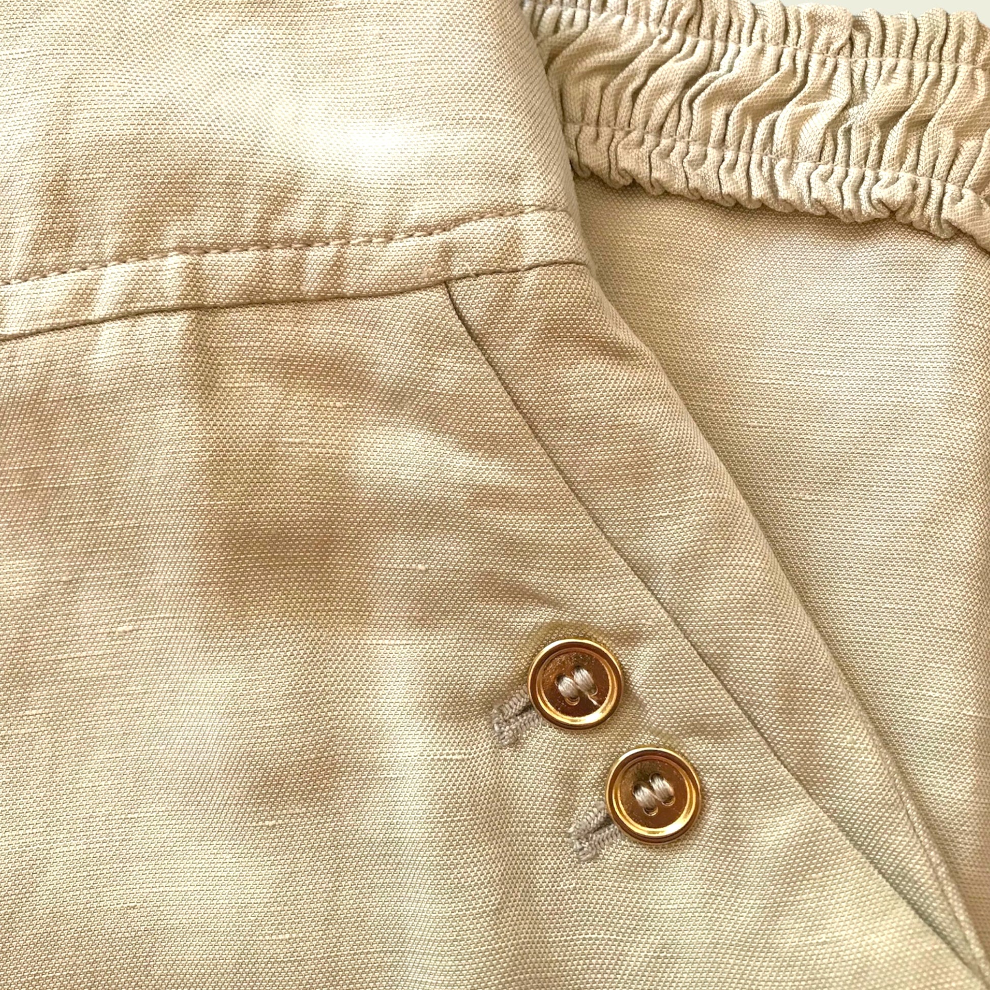 Button detail on tan skirt on beige background
