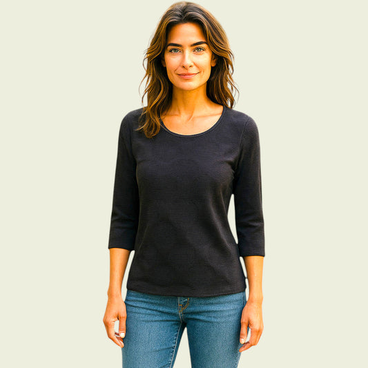 Woman wearing a navy top and blue jeans against a plain background