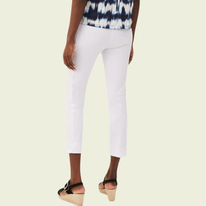 Person wearing white pants and a patterned top on a beige background