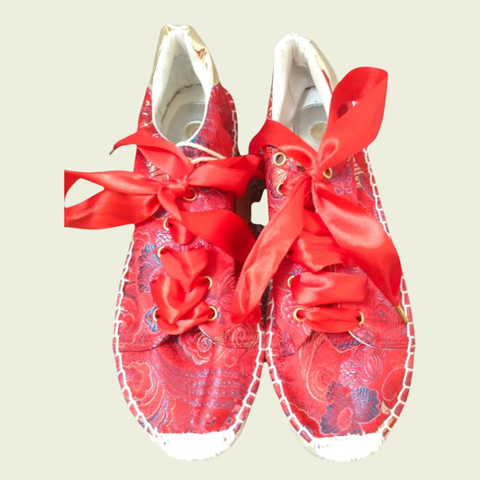 Red floral-patterned shoes with large red bows on a beige background