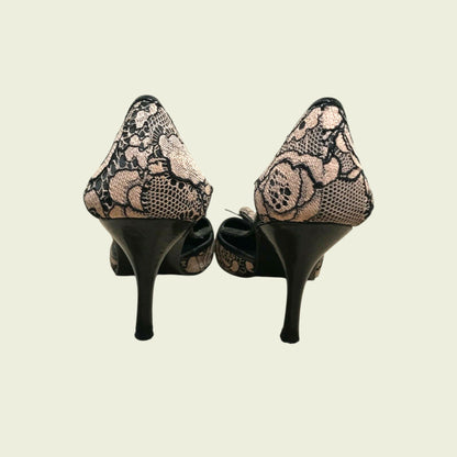 Pair of high-heeled shoes with lace detailing on a beige background