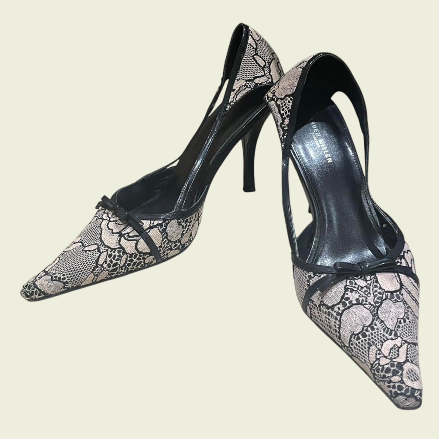 Pair of high-heeled shoes with lace detailing on a beige background