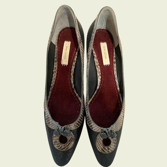 Pair of black high-heeled shoes with snake skin pattern on a beige background