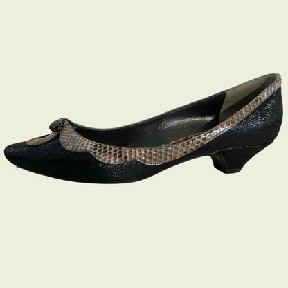 Black shoe with snake print trim on a beige background