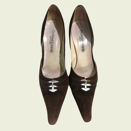 Pair of brown high-heeled shoes with visible brand name on a light beige background