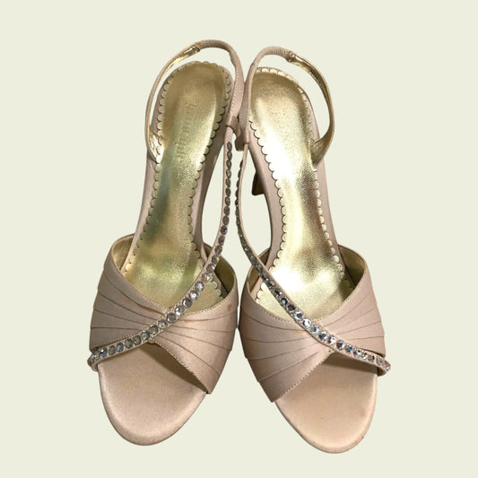 Pair of beige high-heeled sandals with decorative straps on a light background