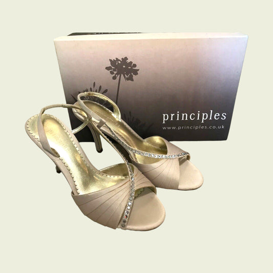 Pair of champagne high-heeled shoes with a 'principles' branded box in the background.
