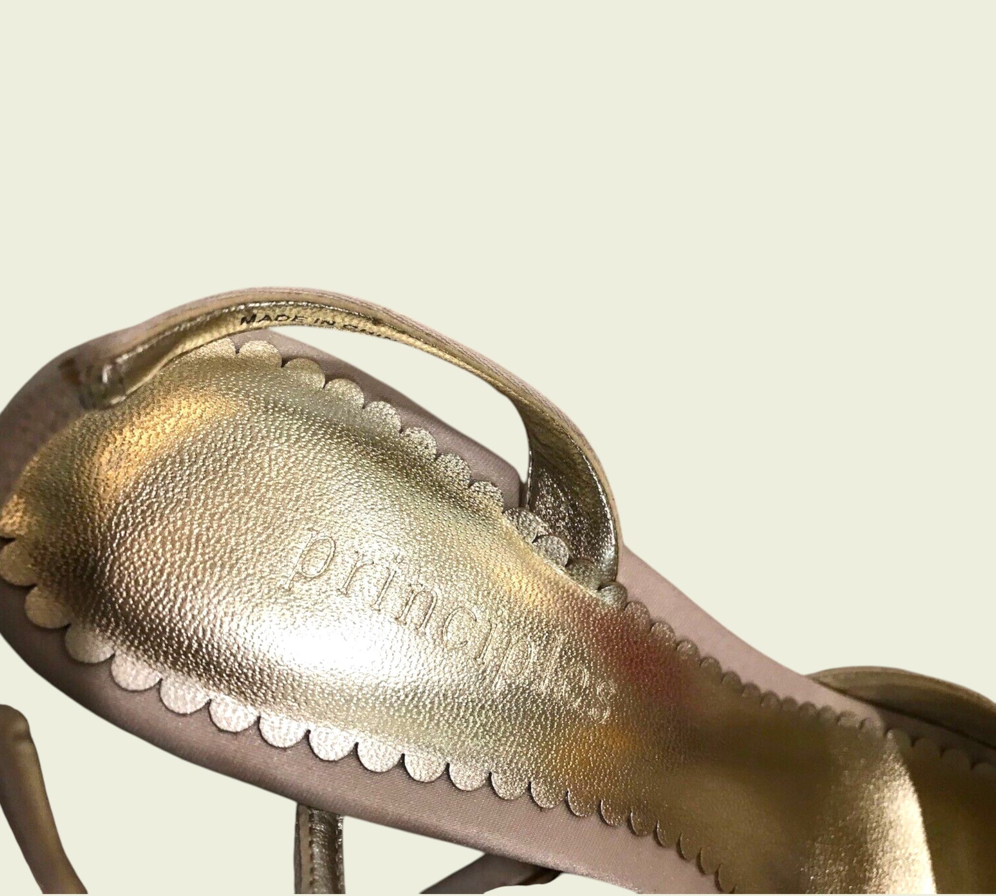 champagne sandal with 'principles' branding on a beige background