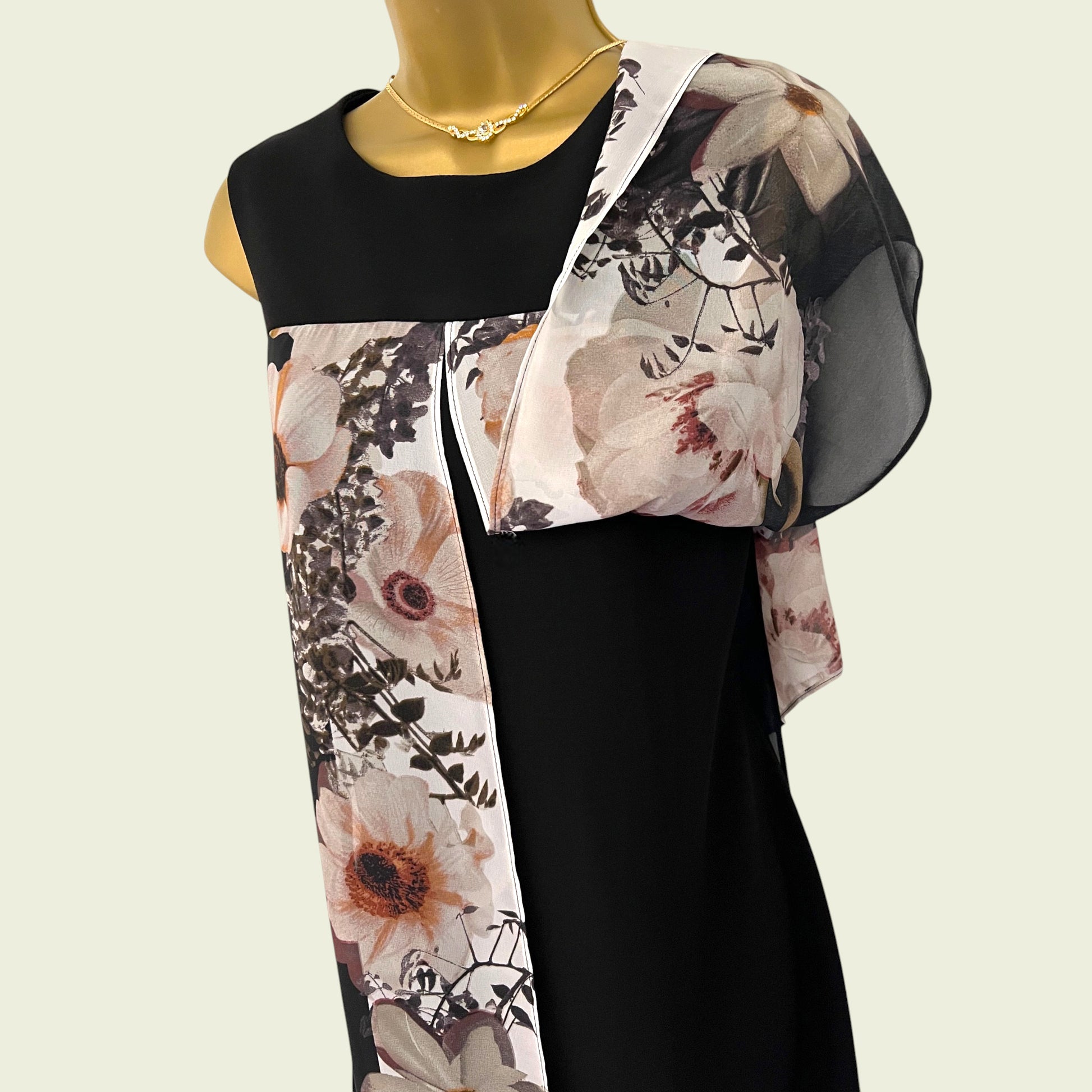 Mannequin wearing a black dress with a floral overlay draped over it on a beige background