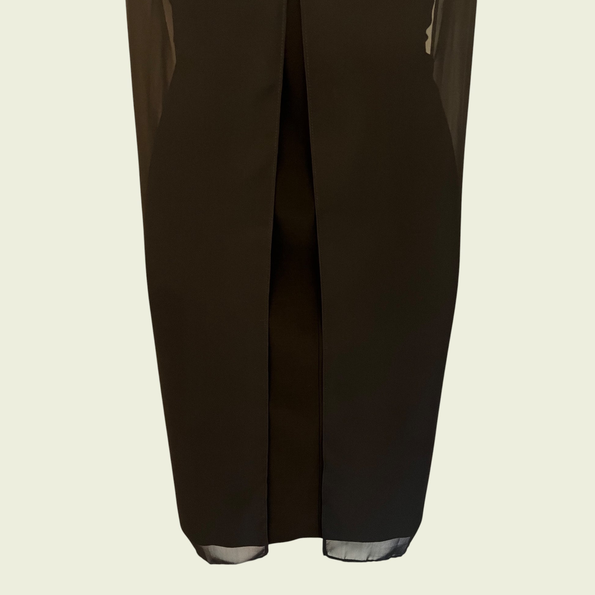 Back of black dress showing pleat on a beige background