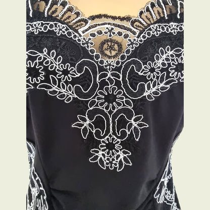 Close-up of navy fabric with intricate white lace embroidery on a beige background