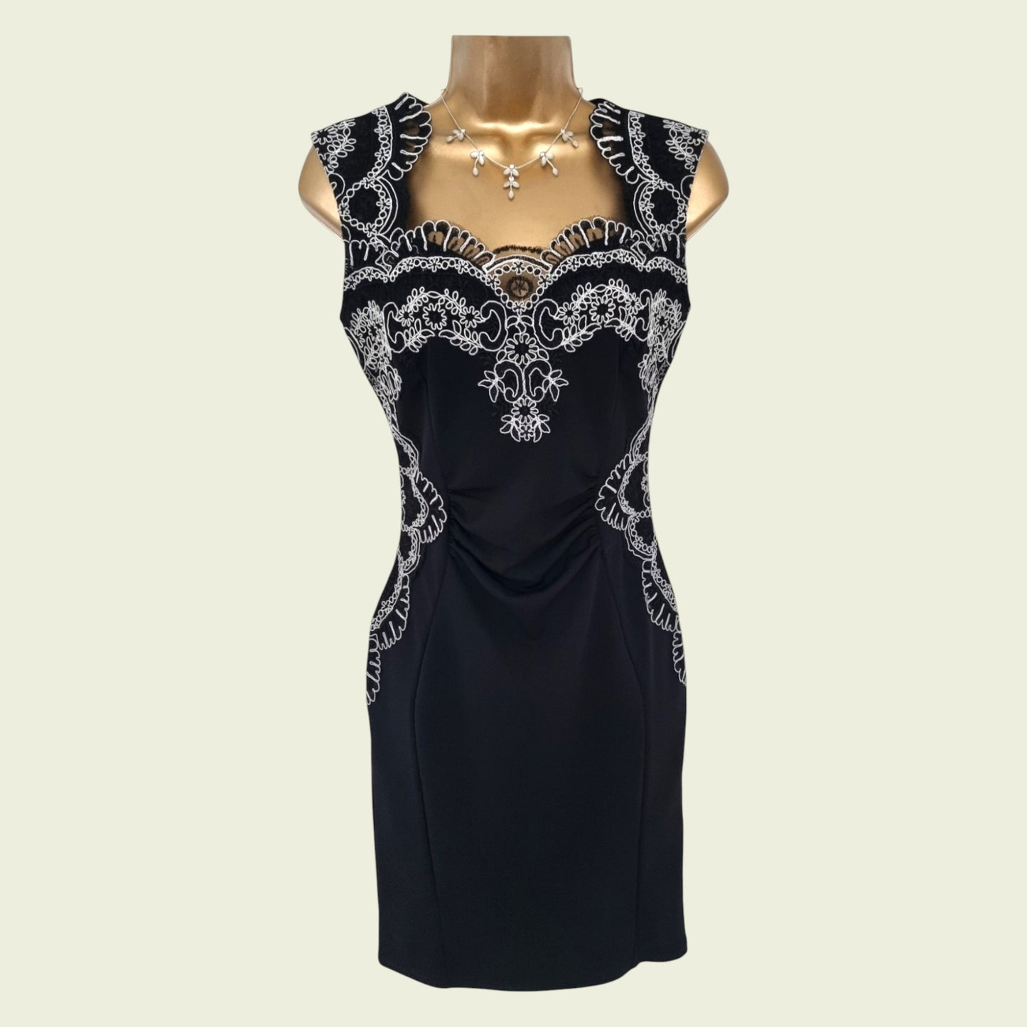 Navy dress with white lace detailing on a mannequin against a beige background