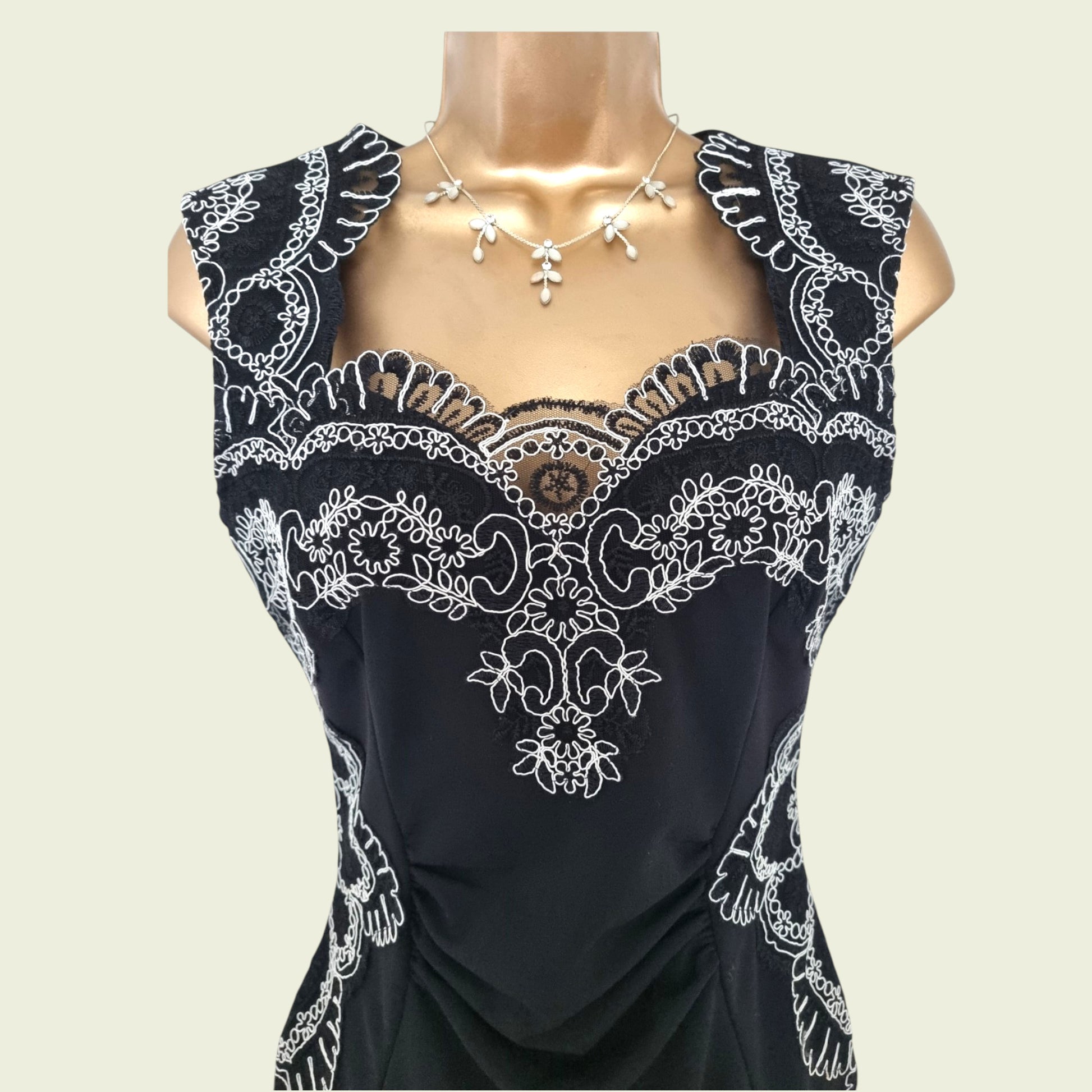 Embroidery detail on navy dress on beige background