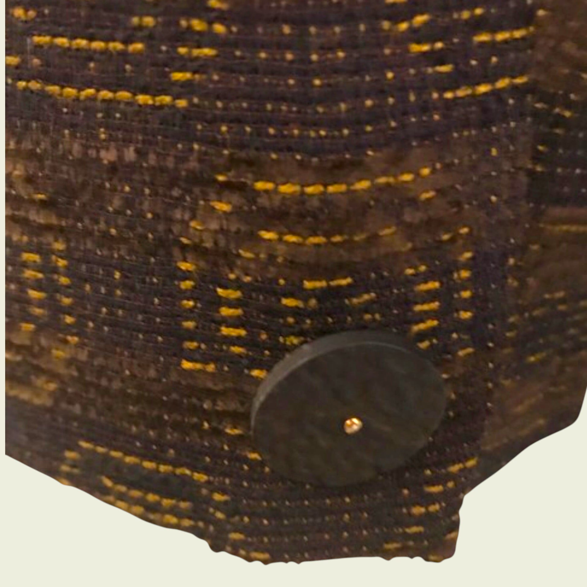 Close-up of a textured fabric with a button on a beige background