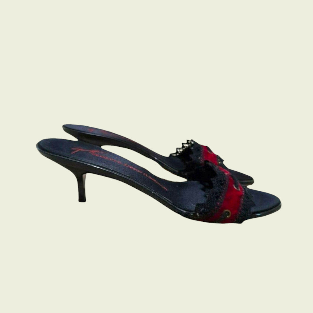 Black high-heeled shoes with red accents on a beige background