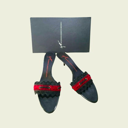 Black high-heeled shoes with red accents and a black box on a beige background
