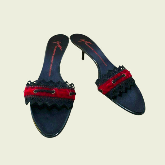 Pair of black heeled shoes with red accents on a beige background
