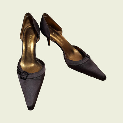 Pair of brown high-heeled shoes with a bow detail on a beige background