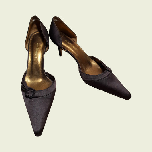 Pair of brown high-heeled shoes with a bow detail on a beige background