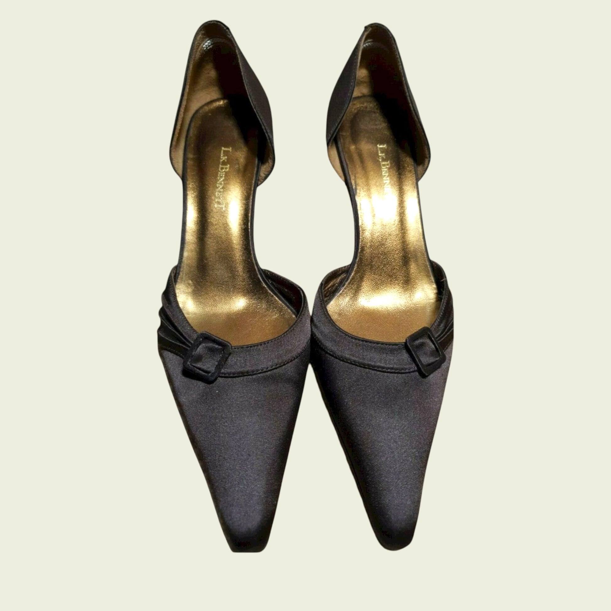Pair of brown high-heeled shoes with gold soles on a beige background