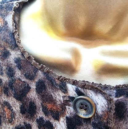 Close-up of a leopard print fabric with a button, featuring a gold and white background.