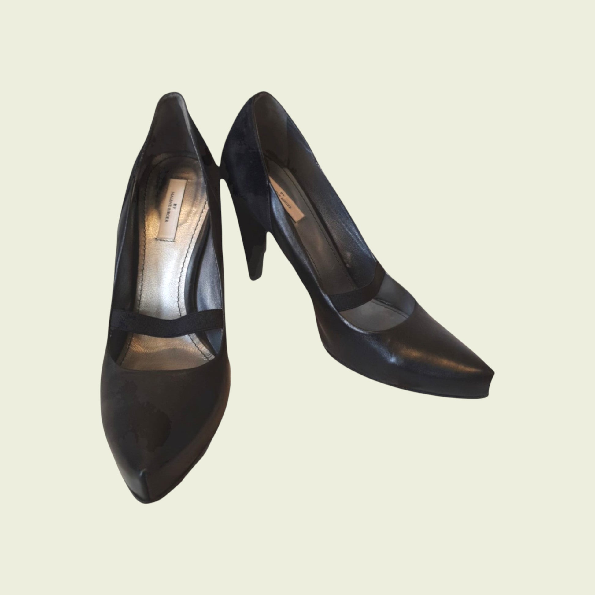 Pair of black high-heeled shoes on a beige background