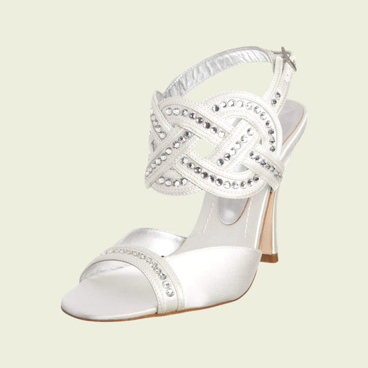 White high-heeled shoe with decorative strap on a light beige background