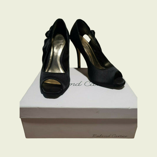 Black high-heeled shoes on a white box with 'Cartier' branding.