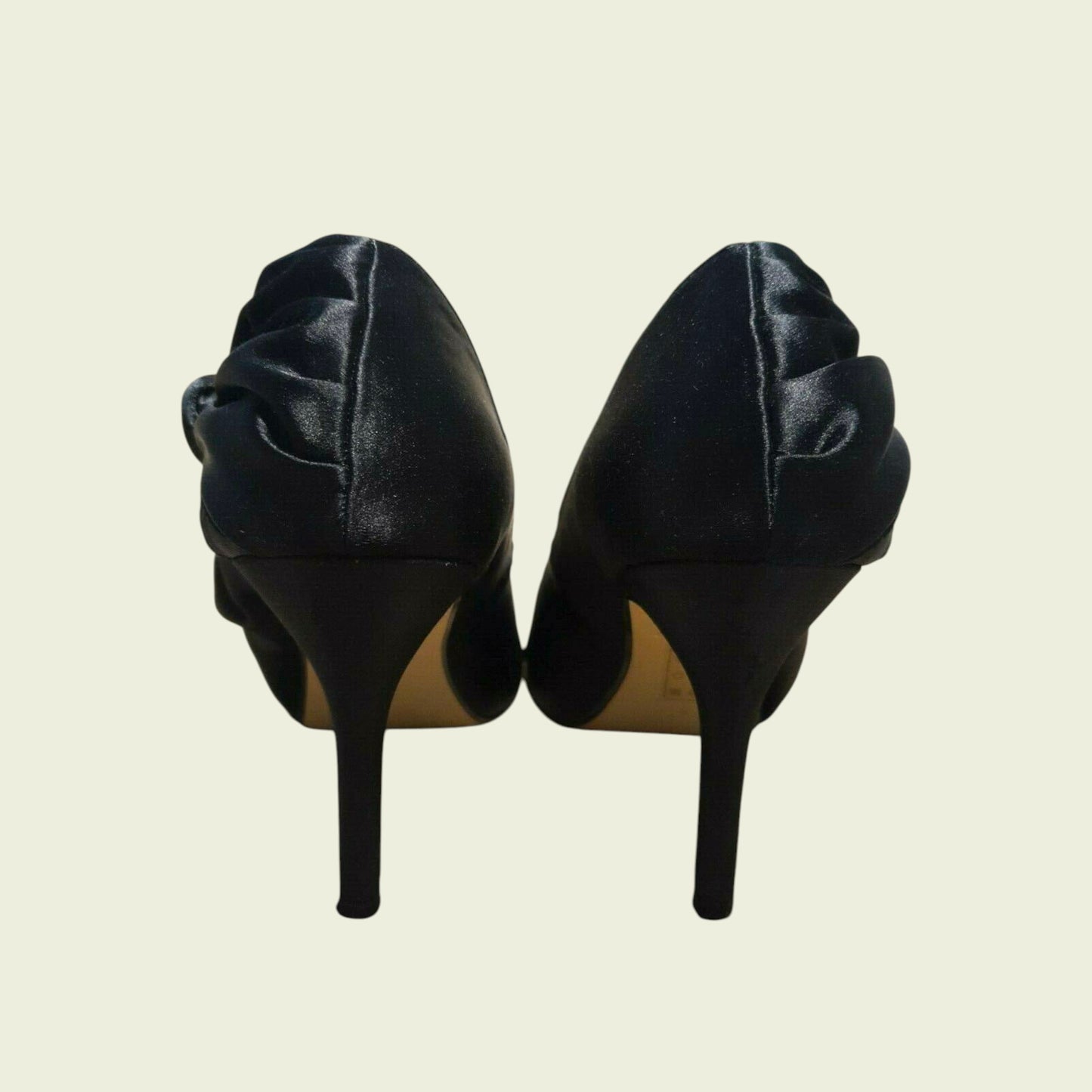 Pair of black high-heeled shoes on a beige background