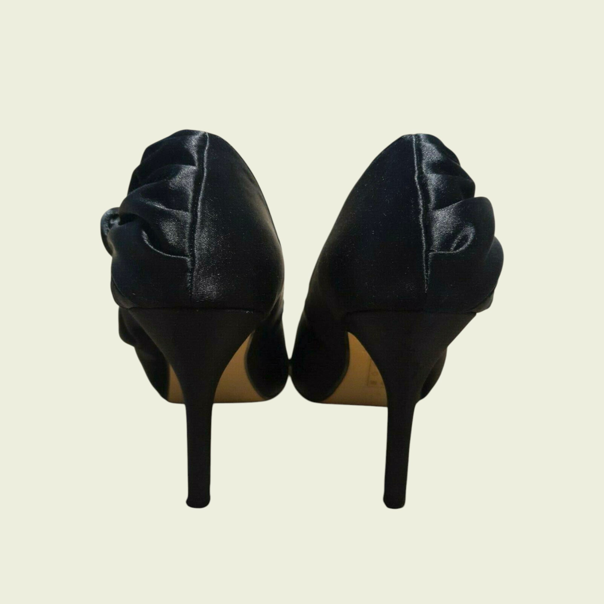 Pair of black high-heeled shoes on a beige background